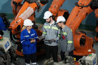 Robot mühendisleri fabrika deposunda robotik kolun bakımı üzerinde çalışıyorlar. İş teknolojisi.