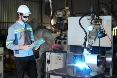 Robot mühendisi fabrika deposunda robotik kolun bakımı üzerinde çalışıyor. İş teknolojisi.