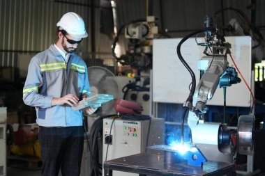 Robot mühendisi fabrika deposunda robotik kolun bakımı üzerinde çalışıyor. İş teknolojisi.