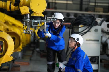 Robot mühendisleri fabrika deposunda robotik kolun bakımı üzerinde çalışıyorlar. İş teknolojisi.