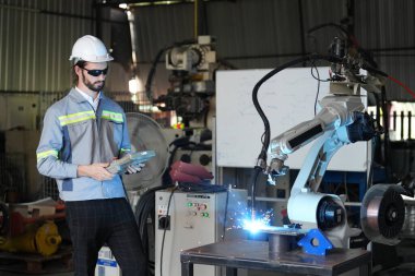 Robot mühendisi fabrika deposunda robotik kolun bakımı üzerinde çalışıyor. İş teknolojisi.