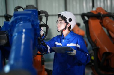 Robot mühendisi fabrika deposunda robotik kolun bakımı üzerinde çalışıyor. İş teknolojisi.