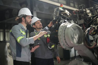 Robot mühendisleri fabrika deposunda robotik kolun bakımı üzerinde çalışıyorlar. İş teknolojisi.