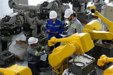 Robot mühendisleri fabrika deposunda robotik kolun bakımı üzerinde çalışıyorlar. İş teknolojisi.