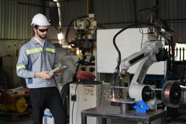 Robot mühendisi fabrika deposunda robotik kolun bakımı üzerinde çalışıyor. İş teknolojisi.
