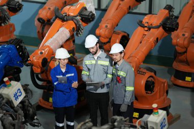 Robot mühendisleri fabrika deposunda robotik kolun bakımı üzerinde çalışıyorlar. İş teknolojisi.