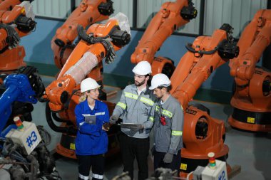 Robot mühendisleri fabrika deposunda robotik kolun bakımı üzerinde çalışıyorlar. İş teknolojisi.