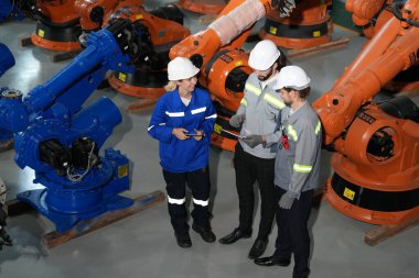 Robot mühendisleri fabrika deposunda robotik kolun bakımı üzerinde çalışıyorlar. İş teknolojisi.