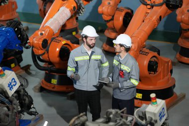 Robot mühendisleri fabrika deposunda robotik kolun bakımı üzerinde çalışıyorlar. İş teknolojisi.