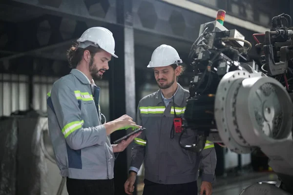 Robot mühendisleri fabrika deposunda robotik kolun bakımı üzerinde çalışıyorlar. İş teknolojisi.