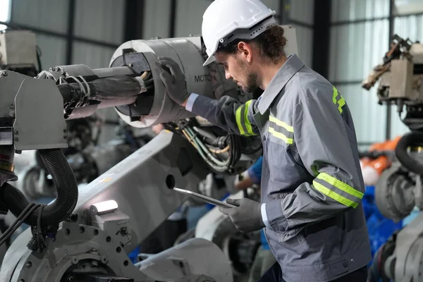 工場倉庫でロボットアームのメンテナンスに取り組むロボットエンジニア 事業技術 — ストック写真