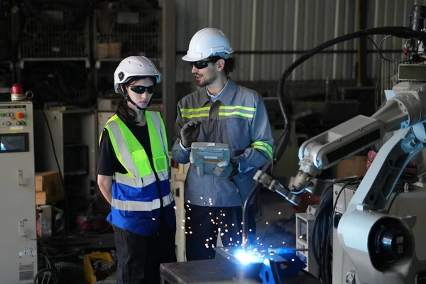 Robot mühendisleri fabrika deposunda robotik kolun bakımı üzerinde çalışıyorlar. İş teknolojisi.