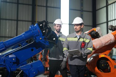 Robot mühendisleri fabrika deposunda robotik kolun bakımı üzerinde çalışıyorlar. İş teknolojisi.