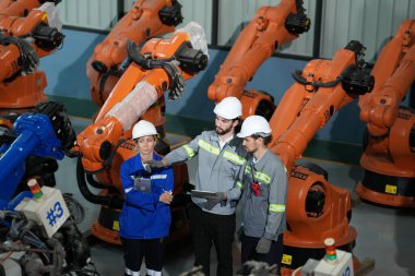 Robot mühendisleri fabrika deposunda robotik kolun bakımı üzerinde çalışıyorlar. İş teknolojisi.