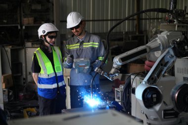 Robot mühendisleri fabrika deposunda robotik kolun bakımı üzerinde çalışıyorlar. İş teknolojisi.