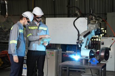 Robot mühendisleri fabrika deposunda robotik kolun bakımı üzerinde çalışıyorlar. İş teknolojisi.