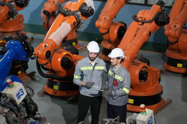 Robot mühendisleri fabrika deposunda robotik kolun bakımı üzerinde çalışıyorlar. İş teknolojisi.
