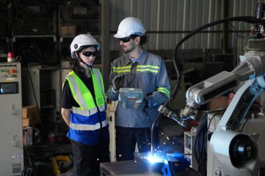Robot mühendisleri fabrika deposunda robotik kolun bakımı üzerinde çalışıyorlar. İş teknolojisi.