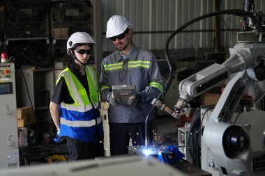 Robot mühendisleri fabrika deposunda robotik kolun bakımı üzerinde çalışıyorlar. İş teknolojisi.