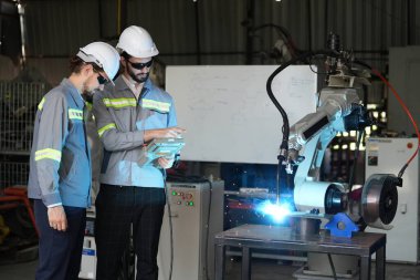 Robot mühendisleri fabrika deposunda robotik kolun bakımı üzerinde çalışıyorlar. İş teknolojisi.