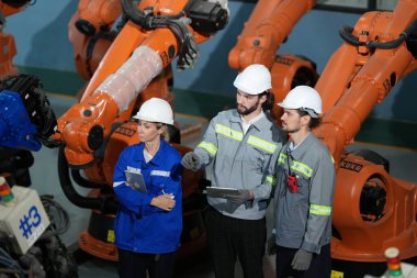 Robot mühendisleri fabrika deposunda robotik kolun bakımı üzerinde çalışıyorlar. İş teknolojisi.