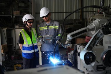 Robot mühendisleri fabrika deposunda robotik kolun bakımı üzerinde çalışıyorlar. İş teknolojisi.