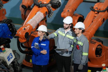 Robot mühendisleri fabrika deposunda robotik kolun bakımı üzerinde çalışıyorlar. İş teknolojisi.