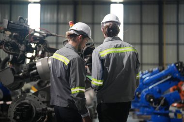 Robot mühendisleri fabrika deposunda robotik kolun bakımı üzerinde çalışıyorlar. İş teknolojisi.