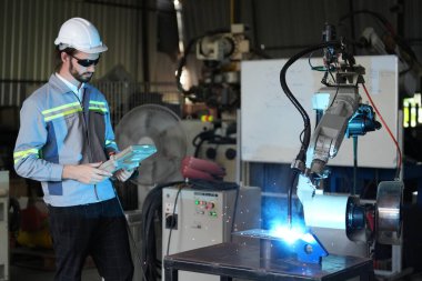 Robot mühendisi fabrika deposunda robotik kolun bakımı üzerinde çalışıyor. İş teknolojisi.