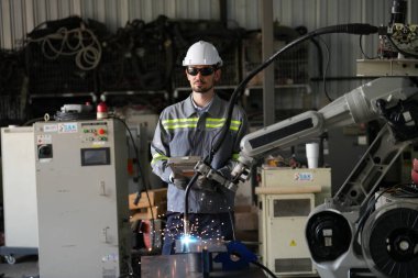 Robot mühendisi fabrika deposunda robotik kolun bakımı üzerinde çalışıyor. İş teknolojisi.