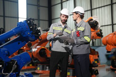 Robot mühendisleri fabrika deposunda robotik kolun bakımı üzerinde çalışıyorlar. İş teknolojisi.