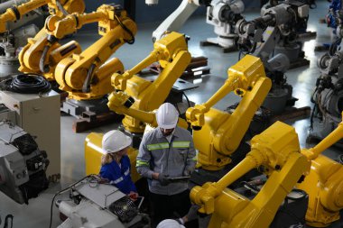 Robot mühendisleri fabrika deposunda robotik kolun bakımı üzerinde çalışıyorlar. İş teknolojisi.