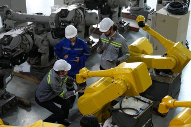 Robot mühendisleri fabrika deposunda robotik kolun bakımı üzerinde çalışıyorlar. İş teknolojisi.