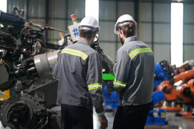 Robot mühendisleri fabrika deposunda robotik kolun bakımı üzerinde çalışıyorlar. İş teknolojisi.