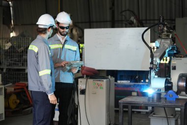 Robot mühendisleri fabrika deposunda robotik kolun bakımı üzerinde çalışıyorlar. İş teknolojisi.