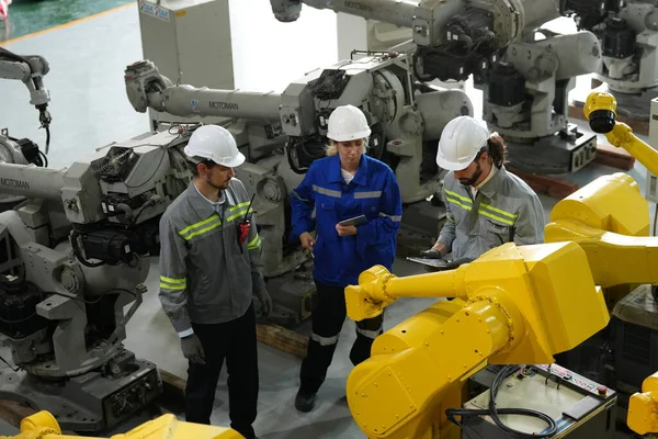 Robot mühendisleri fabrika deposunda robotik kolun bakımı üzerinde çalışıyorlar. İş teknolojisi.