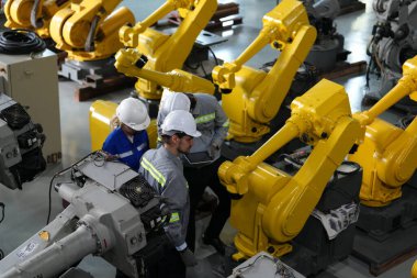 Robot mühendisleri fabrika deposunda robotik kolun bakımı üzerinde çalışıyorlar. İş teknolojisi.