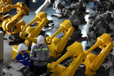 Robot mühendisleri fabrika deposunda robotik kolun bakımı üzerinde çalışıyorlar. İş teknolojisi.