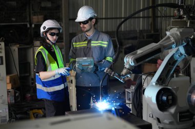 Robot mühendisleri fabrika deposunda robotik kolun bakımı üzerinde çalışıyorlar. İş teknolojisi.