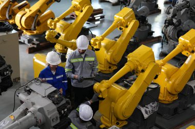 Robot mühendisleri fabrika deposunda robotik kolun bakımı üzerinde çalışıyorlar. İş teknolojisi.