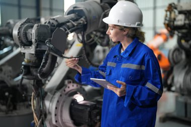 Robot mühendisi fabrika deposunda robotik kolun bakımı üzerinde çalışıyor. İş teknolojisi.