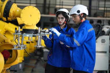 Robot mühendisleri fabrika deposunda robotik kolun bakımı üzerinde çalışıyorlar. İş teknolojisi.