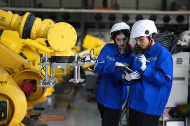 Robot mühendisleri fabrika deposunda robotik kolun bakımı üzerinde çalışıyorlar. İş teknolojisi.