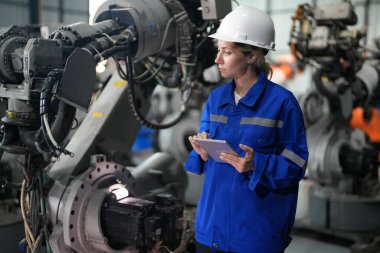 Robot mühendisi fabrika deposunda robotik kolun bakımı üzerinde çalışıyor. İş teknolojisi.