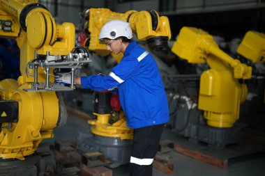 Robot mühendisi fabrika deposunda robotik kolun bakımı üzerinde çalışıyor. İş teknolojisi.
