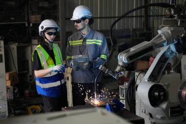 Robot mühendisleri fabrika deposunda robotik kolun bakımı üzerinde çalışıyorlar. İş teknolojisi.