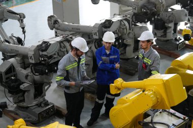 Robot mühendisleri fabrika deposunda robotik kolun bakımı üzerinde çalışıyorlar. İş teknolojisi.