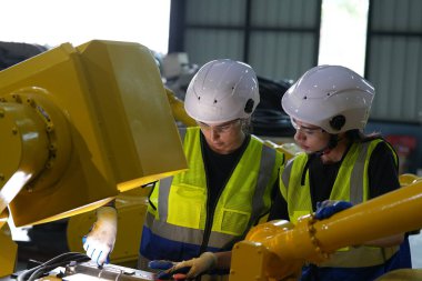 Robot mühendisleri fabrika deposunda robotik kolun bakımı üzerinde çalışıyorlar. İş teknolojisi.