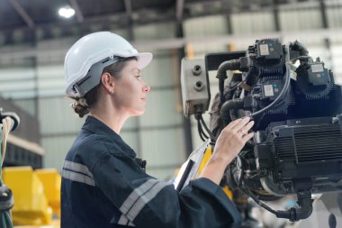 Teknisyen bir robot kolu dijital tabletle programlar ve bir fabrikada robot montajı yapar. Çırak mühendisleri fabrikada robot programlıyorlar..