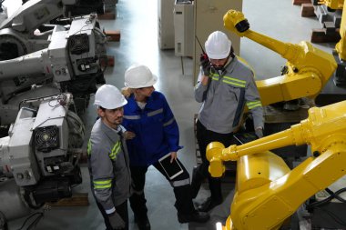 Robot mühendisleri fabrika deposunda robotik kolun bakımı üzerinde çalışıyorlar. İş teknolojisi.